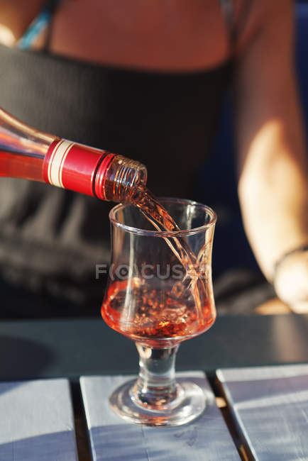 Mulher derramando vinho rosa para vidro — Fotografia de Stock