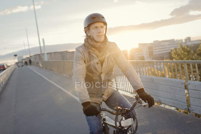Man riding bike on bridge at sunset, selective focus — Stock Photo