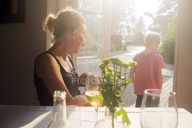 Mother looking at son standing in doorway to backyard at restaurant — Stock Photo
