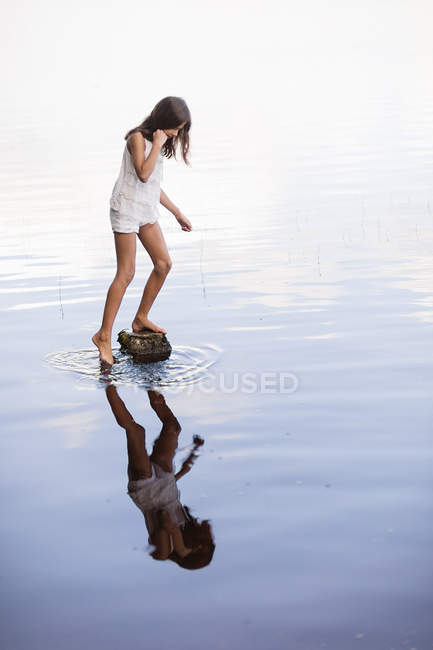 Mädchen mit braunen Haaren steht auf Felsen im Fluss — Stockfoto