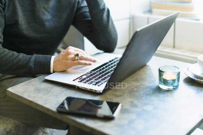 Colpo ritagliato di uomo con anello sul dito che lavora al computer portatile in caffè — Foto stock