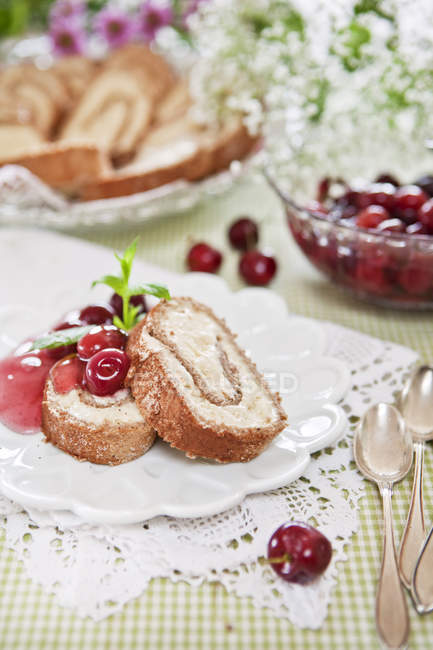 Portion of gingerbread swiss rolls with cherries and sauce — Stock Photo
