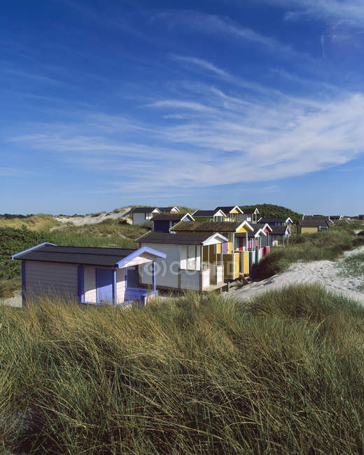 Cabanas na praia gramada em luz solar brilhante — Fotografia de Stock