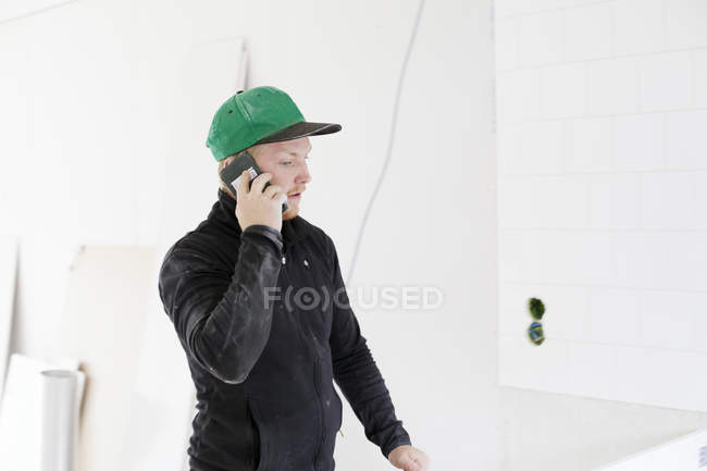 Carpinteiro falando no telefone celular no interior de casa — Fotografia de Stock