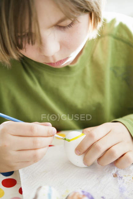 Девушка рисует яйцо, избирательный фокус — стоковое фото