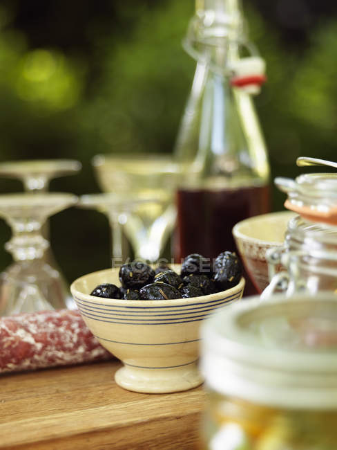 Tigela de azeitonas pretas na mesa servida — Fotografia de Stock