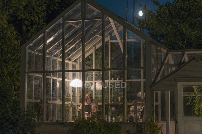 Front view of woman inside of greenhouse at night — Stock Photo