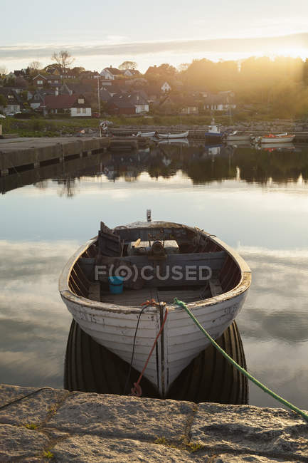 Лодка пришвартована в канале с заходящим солнцем — стоковое фото