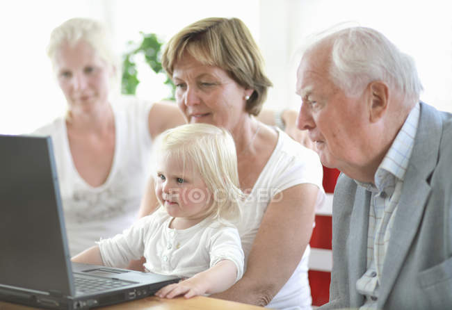 Мультипоколение семьи с девушкой с помощью ноутбука — стоковое фото