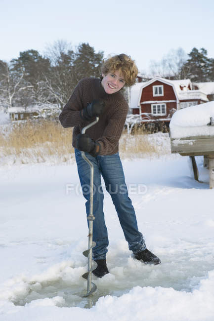 Retrato de adolescente fazendo buraco para pesca no gelo — Fotografia de Stock