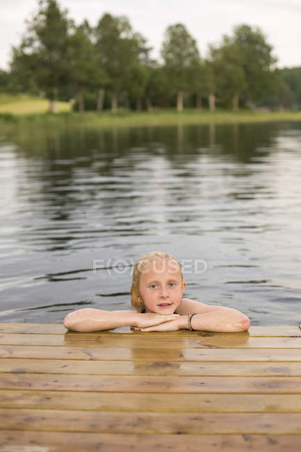 Retrato de niña en el lago con las manos en la barbilla - foto de stock