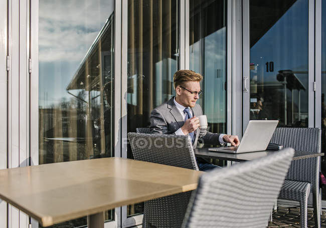 Empresário no terraço do café usando laptop — Fotografia de Stock