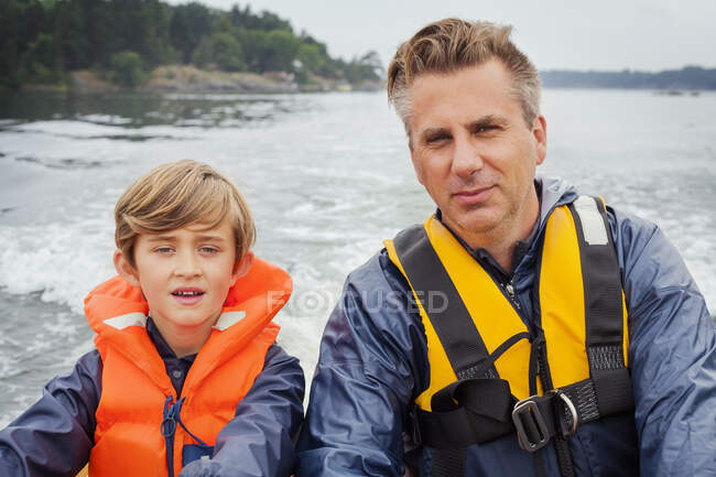 Отец и сын на моторной лодке — стоковое фото