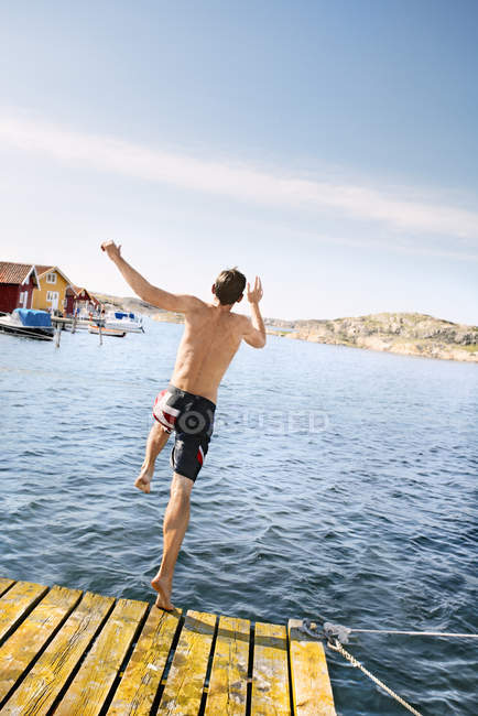Rear view of man jumping into water — Stock Photo
