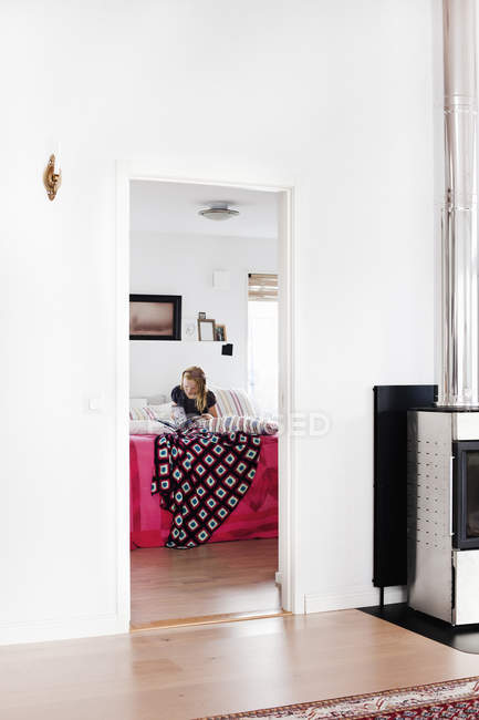 Mädchen liest Buch auf dem Bett im Haus — Stockfoto