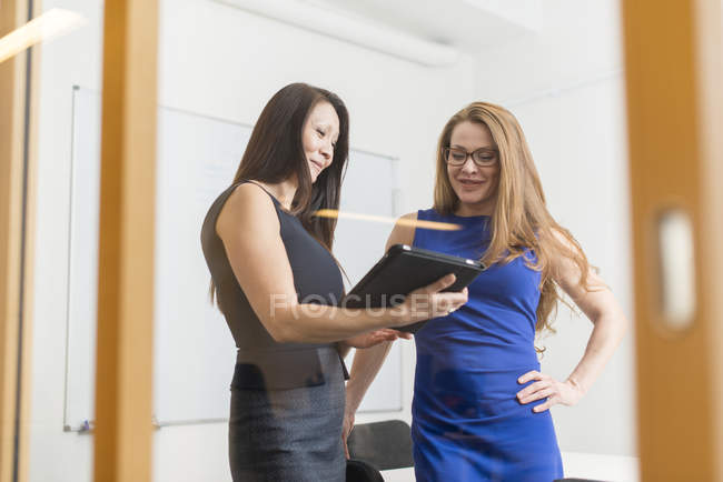 Бізнес-леді розмовляють і використовують цифровий планшет, вибірковий фокус — стокове фото
