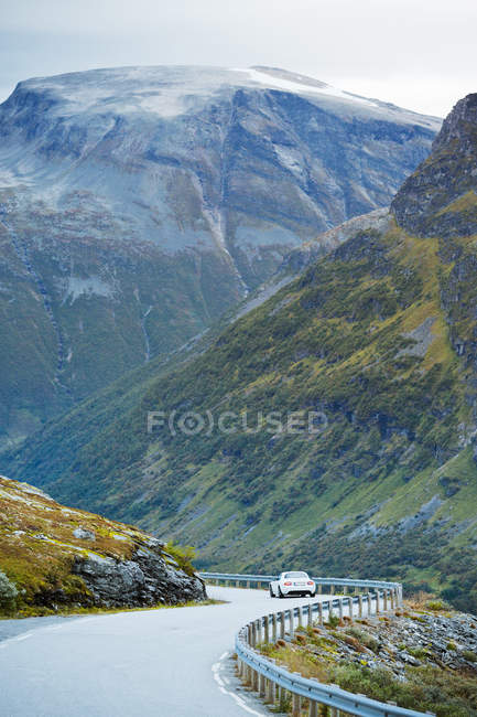 Coche conduciendo a lo largo de Trollstigen carretera, serpenteando en valle de montaña - foto de stock