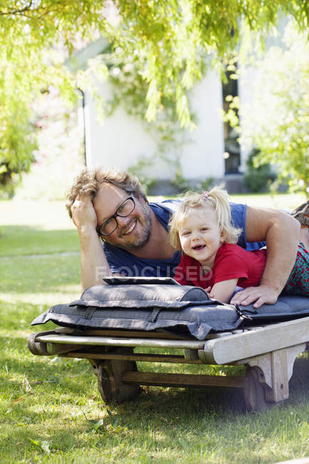 Ritratto di figlia con padre sdraiato sulla sdraio e con tablet pc — Foto stock