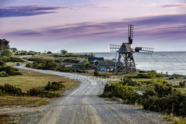 Coastal winding road and windmill under cloudy sky — Stock Photo
