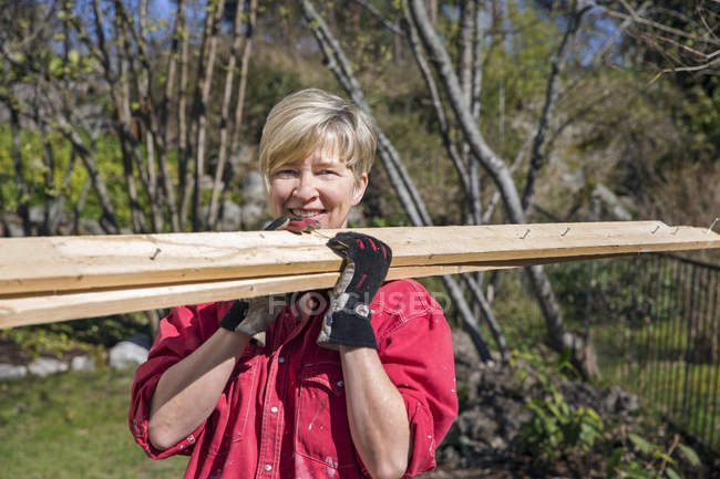 Woman carrying planks, focus on foreground — Stock Photo