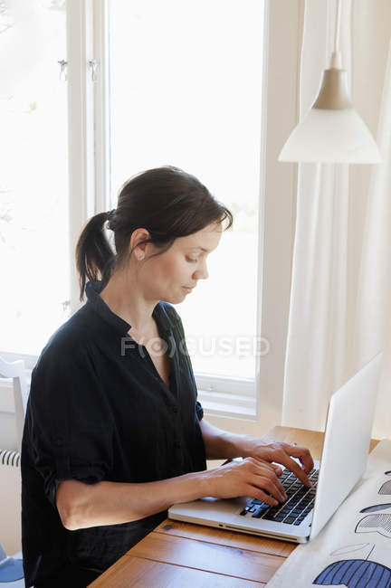 Donna che naviga in rete sul computer portatile a casa — Foto stock