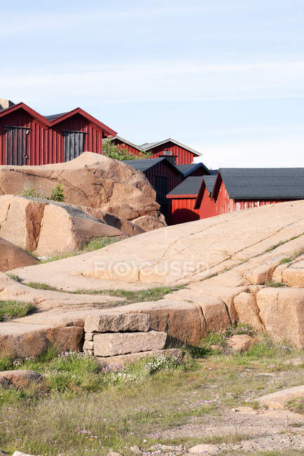 Edifícios vermelhos atrás das rochas sob o céu azul — Fotografia de Stock