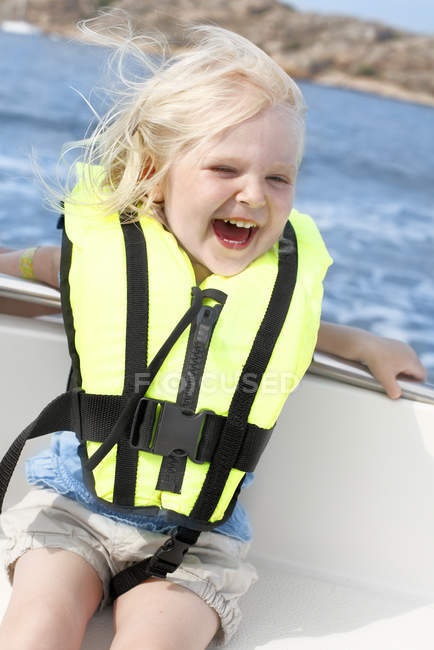 Girl sitting in boat in life jacket and having fun — Stock Photo