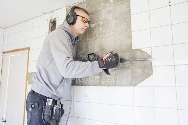 Young man in protective eyewear renovating house — Stock Photo