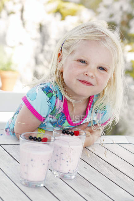 Portrait of girl with two glasses of milkshake with blueberries — Stock Photo