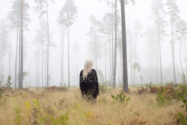 Femme debout dans le brouillard regardant loin — Photo de stock