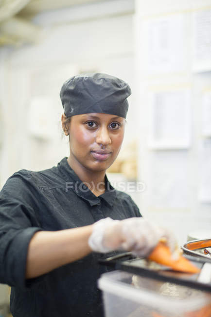 Mulher olhando para a câmera na cozinha do café, foco diferencial — Fotografia de Stock