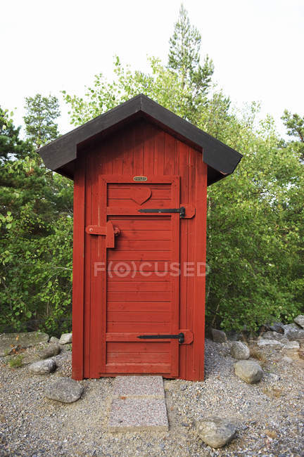 Вид на окрашенный в красный цвет деревянный открытый туалет — стоковое фото