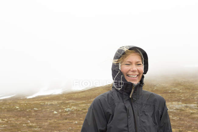 Lächelnde Frau im Regenmantel, Fokus auf den Vordergrund — Stockfoto