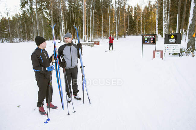 Esquiadores em pé na neve e conversando ao ar livre no inverno — Fotografia de Stock