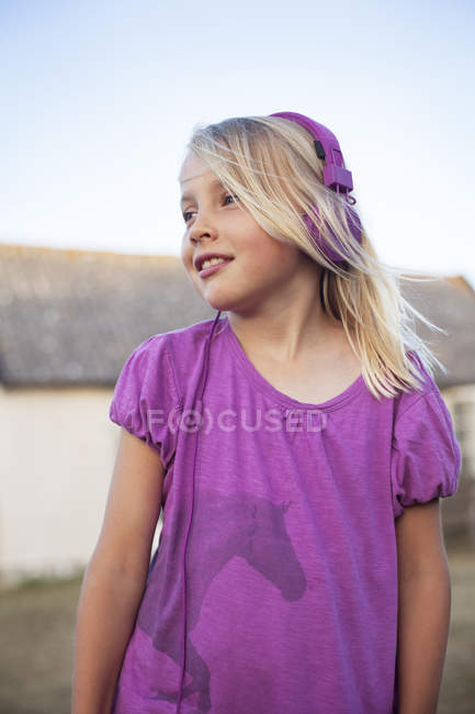 Girl with headphones in backyard, focus on foreground — Stock Photo