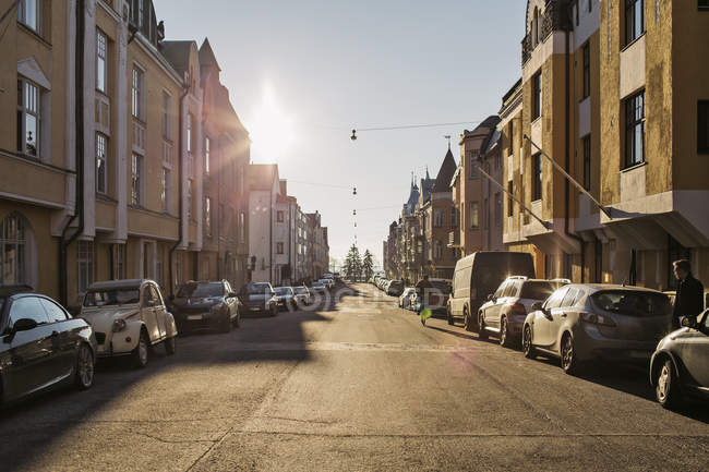 Blick entlang der sonnenbeschienenen Straße mit Autos und Fußgängern, Helsinki — Stockfoto