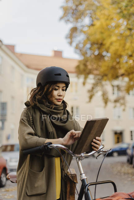 Young woman using digital tablet, standing by bicycle — Stock Photo