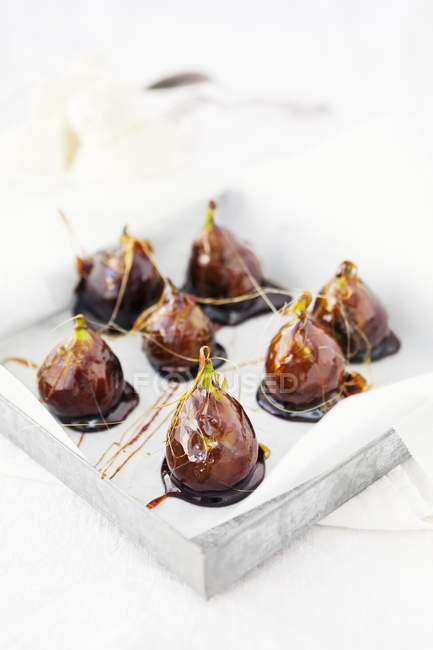 Glazed figs with wax paper on tray — Stock Photo