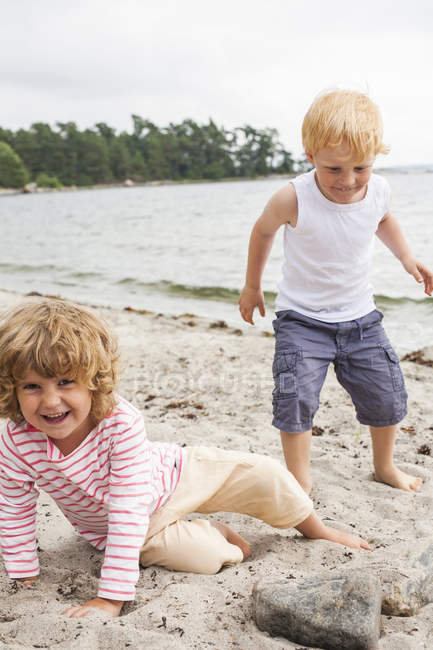 Vista frontal de niña y niño en la playa - foto de stock