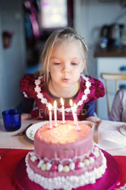 Chica soplando velas en pastel de cumpleaños, enfoque selectivo - foto de stock