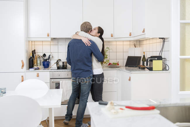 Casal abraçando na cozinha doméstica, foco diferencial — Fotografia de Stock