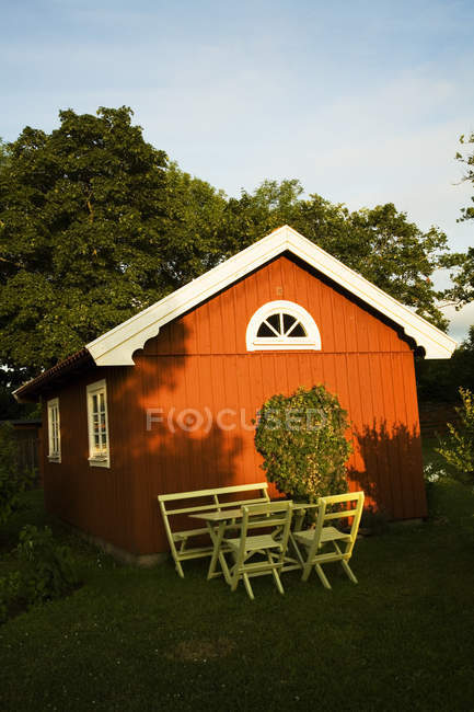 Falu cabaña roja con mesa y sillas a la luz del sol - foto de stock
