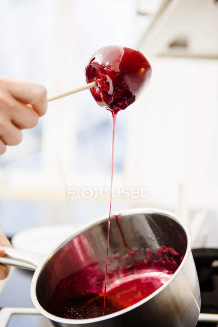 Female hand dipping apple in syrup — Stock Photo