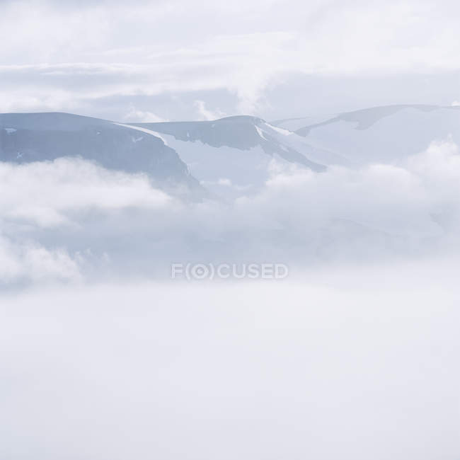 Montañas cubiertas de nieve cubiertas de nubes bajas - foto de stock