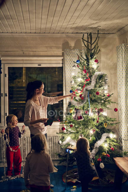 Madre con hijas decorando árbol de Navidad - foto de stock
