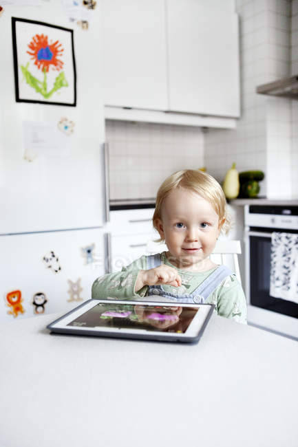 Хлопчик використовує цифровий планшет на кухні, вибірковий фокус — стокове фото