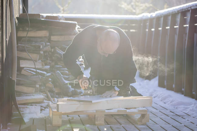 Чоловік ріже деревину головоломкою, фокус на передньому плані — стокове фото