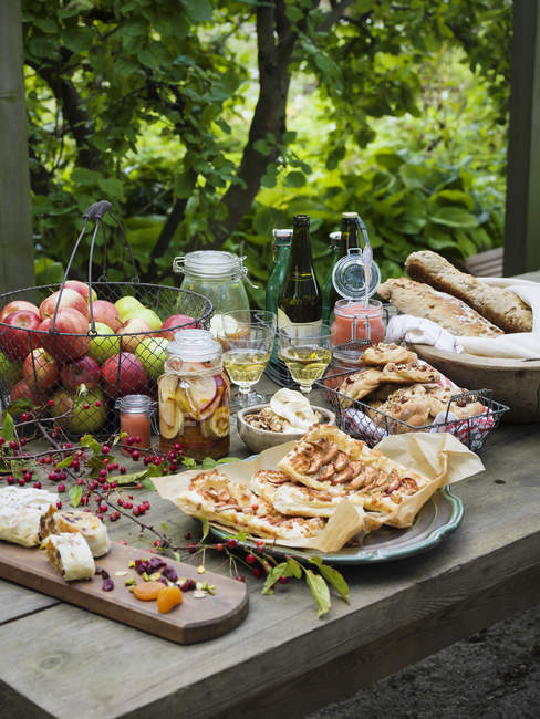 Manzanas, pasteles y pan servido picnic en la mesa - foto de stock
