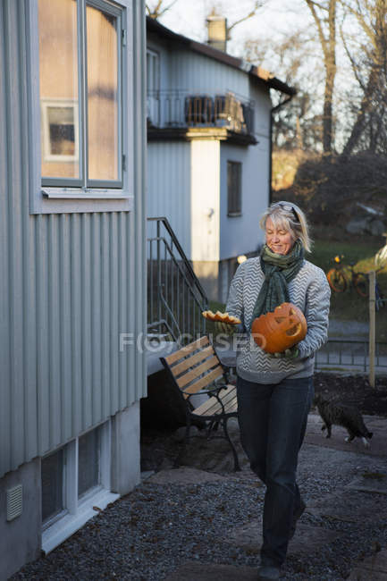 Mature woman carrying carved pumpkin — Stock Photo