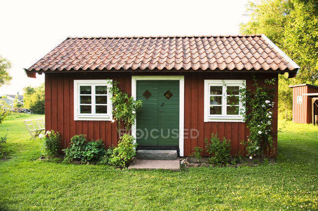 Kleine falu rote Hausfassade mit grünem Gras und Büschen — Stockfoto
